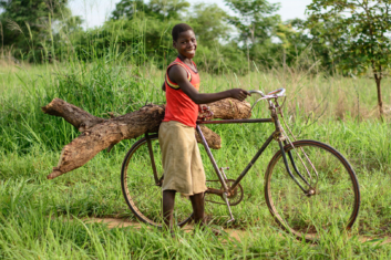 African boy with firewood on his bike