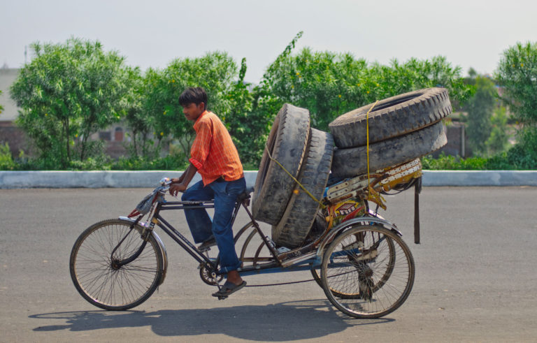A rickshaw loaded with truck tires.