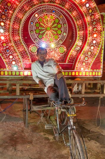 A rickshaw carries a neon wedding decoration.