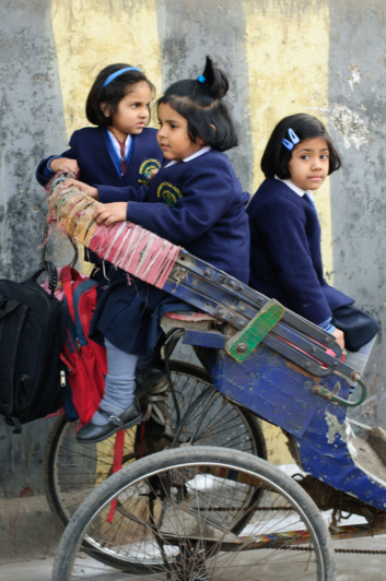 Schoolgirls sit in a rickshaw in Delhi, India.