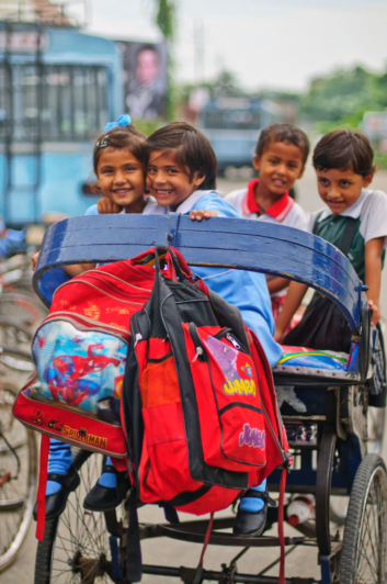 Indian schoolkids sit in a rickshaw.