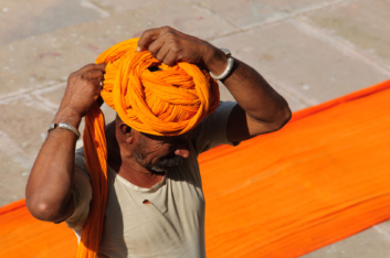An Indian man winds his turban around his head.