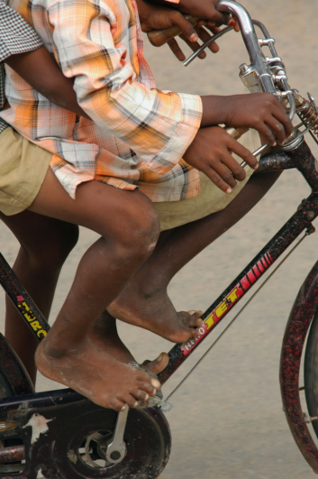Two boys sit on a bicycle in India.