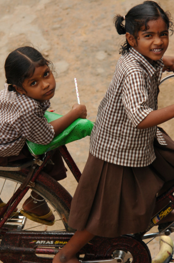 Two Indian girls sit on a bicycle.