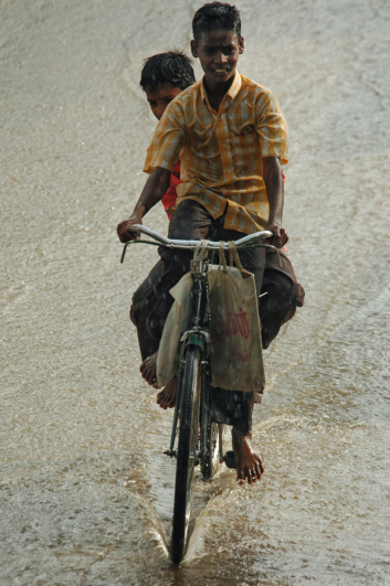 Kids enjoy pedaling through the monsoon rains in India.