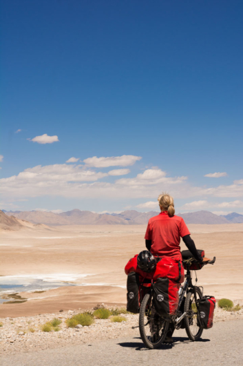 A touring cyclist looks out over the landscape surrounding the pamir highway.