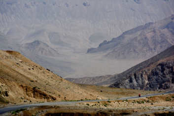 A small red cyclist pedals the Pamir highway.