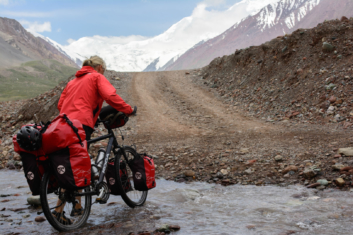 pushing a bicycle across a river in kyrgyzstan on the pamir highway