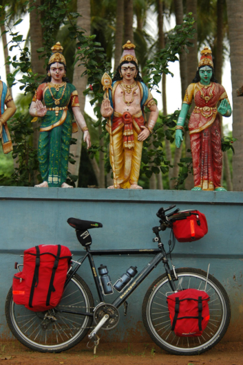 A fully loaded bicycle is leaned against a temple wall in India.
