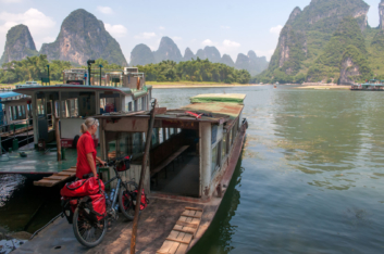 Cycle tourist takes a boat across a river in China