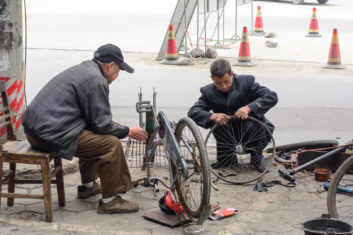 Two Chinese men repair a bicycle