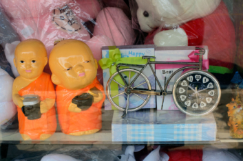 A small bicycle clock sits in a Thai store window.