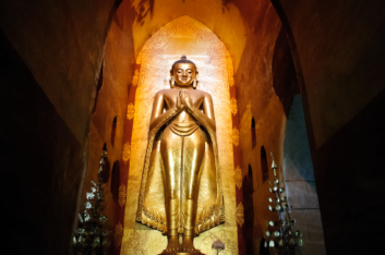 A tall, golden Buddha statue in Bagan, Myanmar.