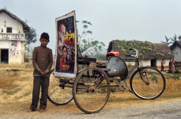 A child stands next to a rickshaw on the Nepalese terai.
