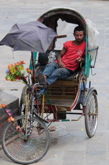 A chauffeur sits in his rickshaw, waiting for customers in Kathmandu, Nepal.