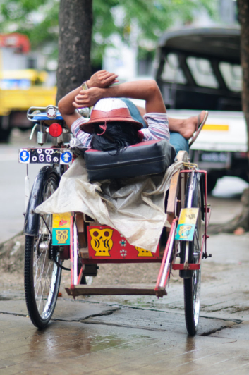 A rickshaw chauffer relaxes on his rickshaw in Yangon, Myanmar.