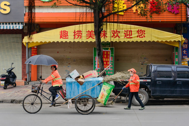 Two cycling Chinese street cleaners.