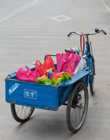 A blue cargo bike is full of brightly colored bags in China.