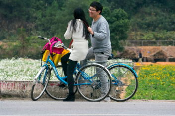 Chinese cyclists smile at each other.