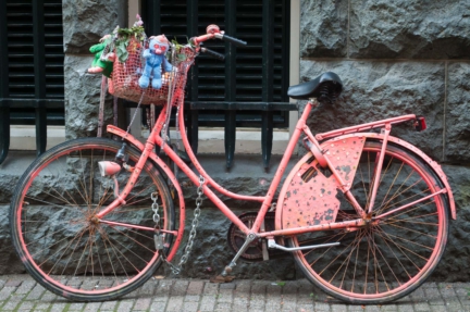 A pink bicycle leans against a wall in Amsterdam, the Netherlands.