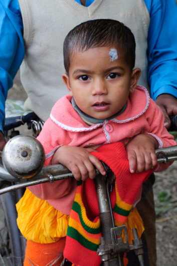 A small Bangladeshi boy sits on a bike frame in Bangladesh.