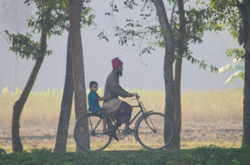 A father and son ride a bike in Bangladesh.