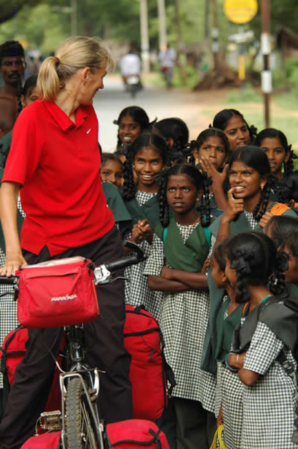 Curious Indian schoolgirls gather around a Western female cyclist.