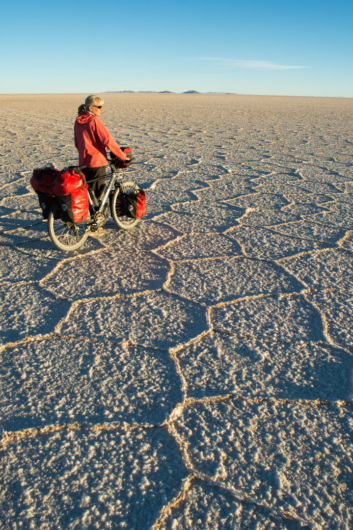 A touring cyclist stands looking out over the salar de uyuni in Bolivia